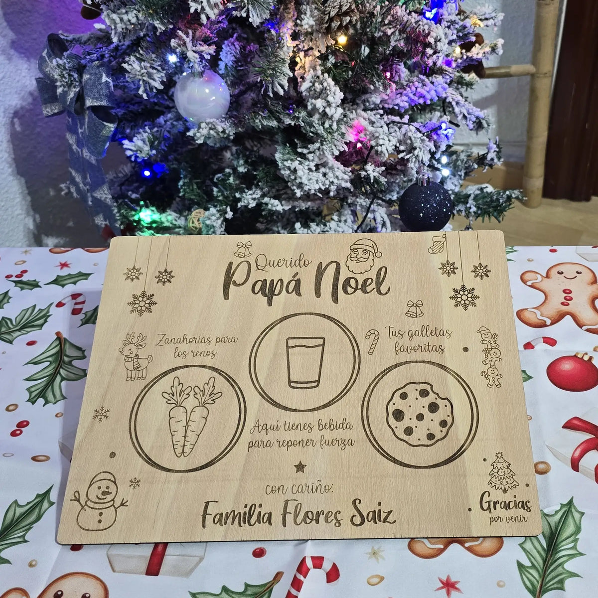 Tabla de Papá Noel grabada con láser con zanahorias para los renos, vaso de bebida y galletas, sobre una mesa navideña