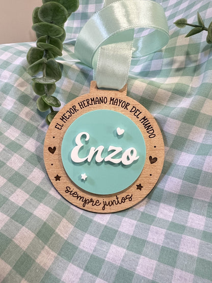 Medalla de hermano mayor de madera con nombre Enzo en metacrilato blanco sobre círculo turquesa y lazo mint, Lunera